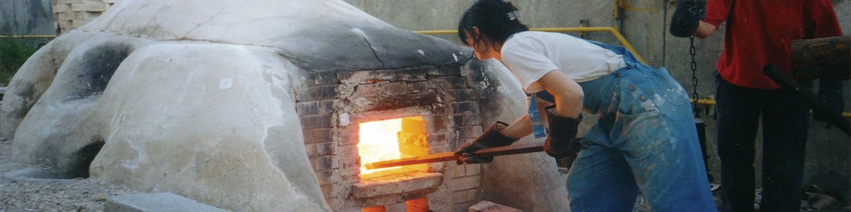Woman stoking fire inside a large kiln