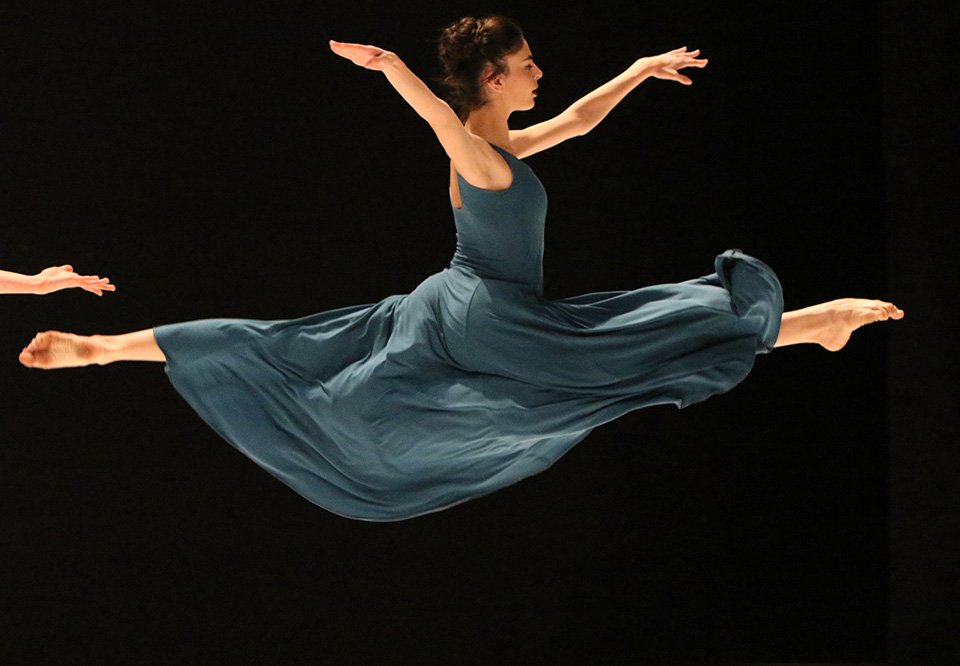 Female ballet dancer in dress leaping in the air